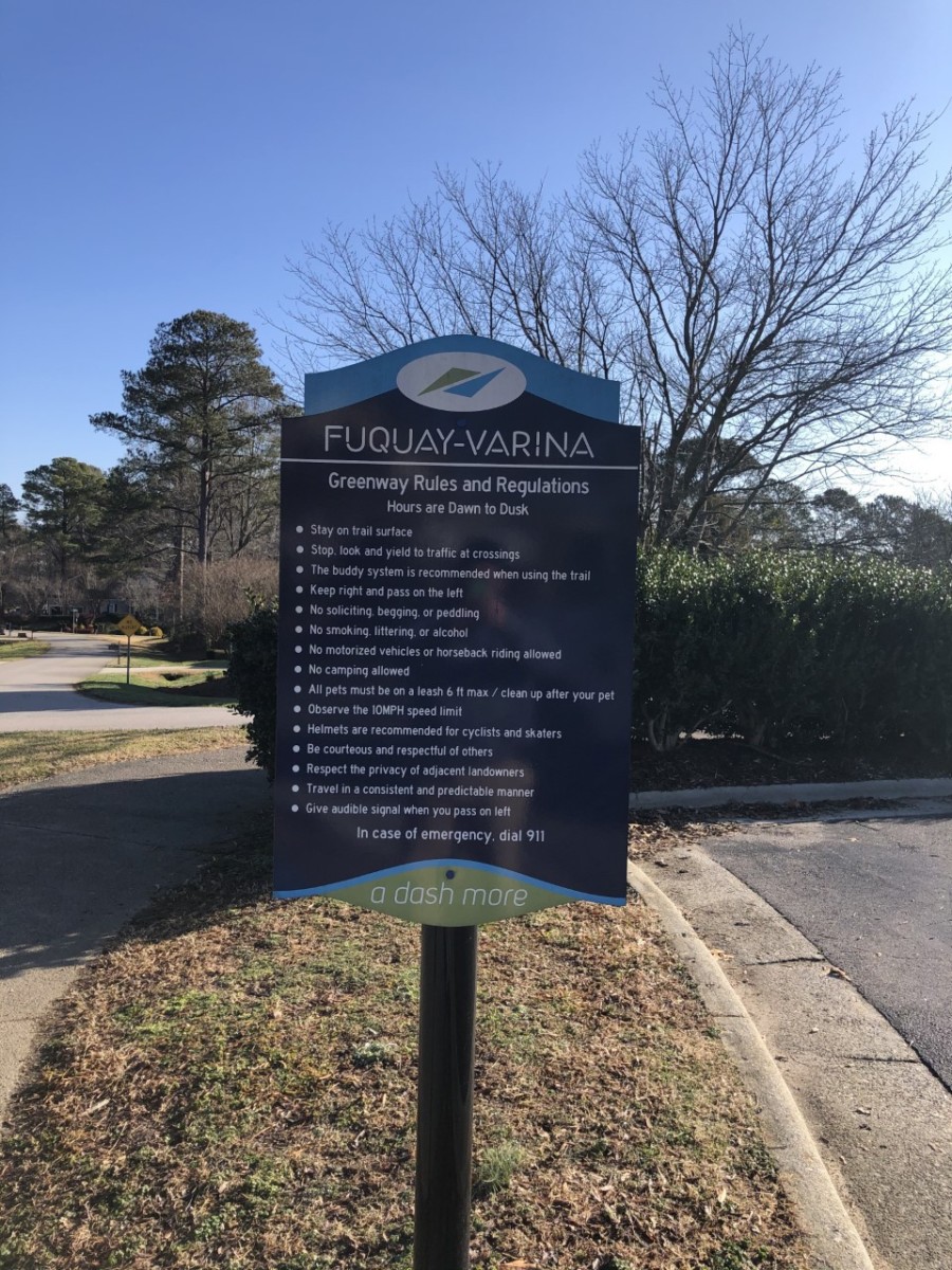 A well-designed informational sign with clear text, contrasting colors, and a company logo, placed at a business entrance for easy visibility.